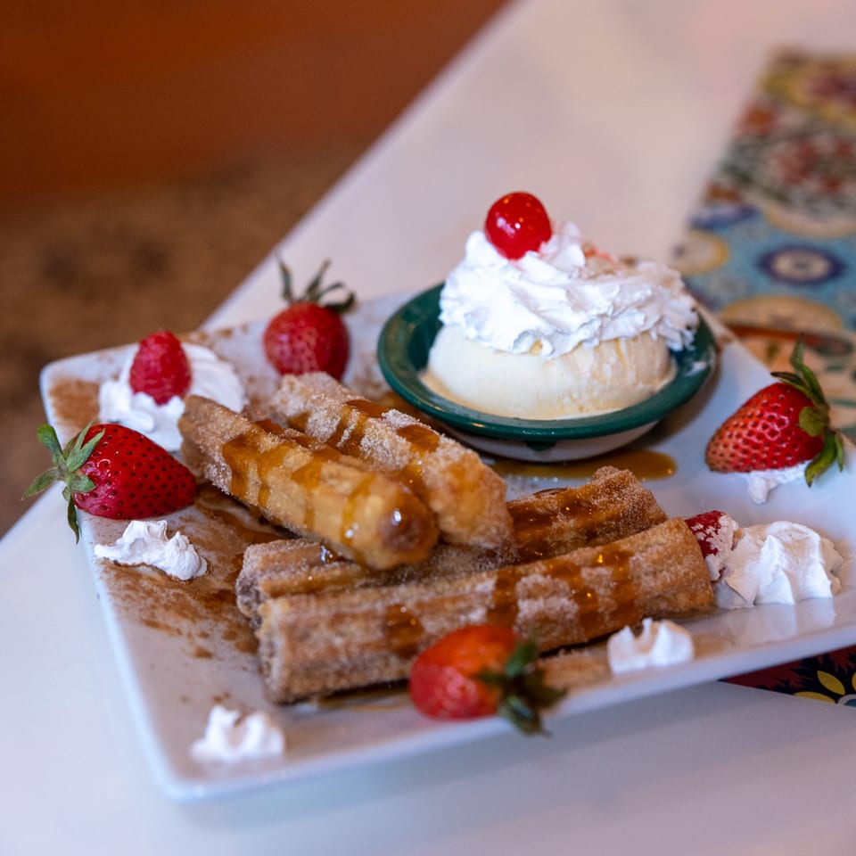 Churros drizzled with caramel, served with vanilla ice cream, whipped cream, and fresh strawberries.
