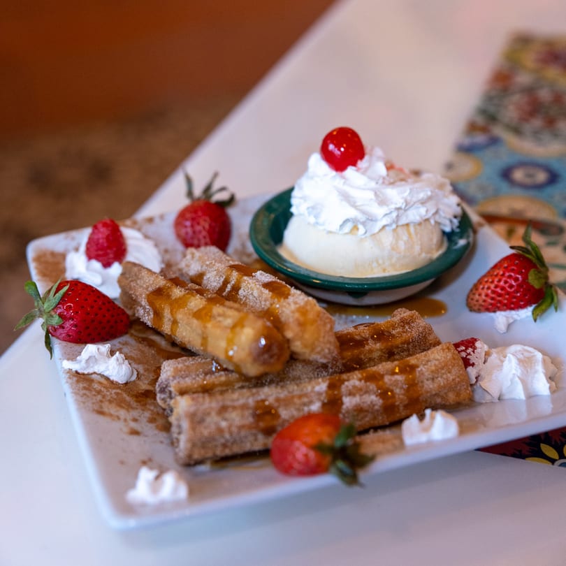 Churros drizzled with caramel, served with vanilla ice cream, whipped cream, and fresh strawberries.